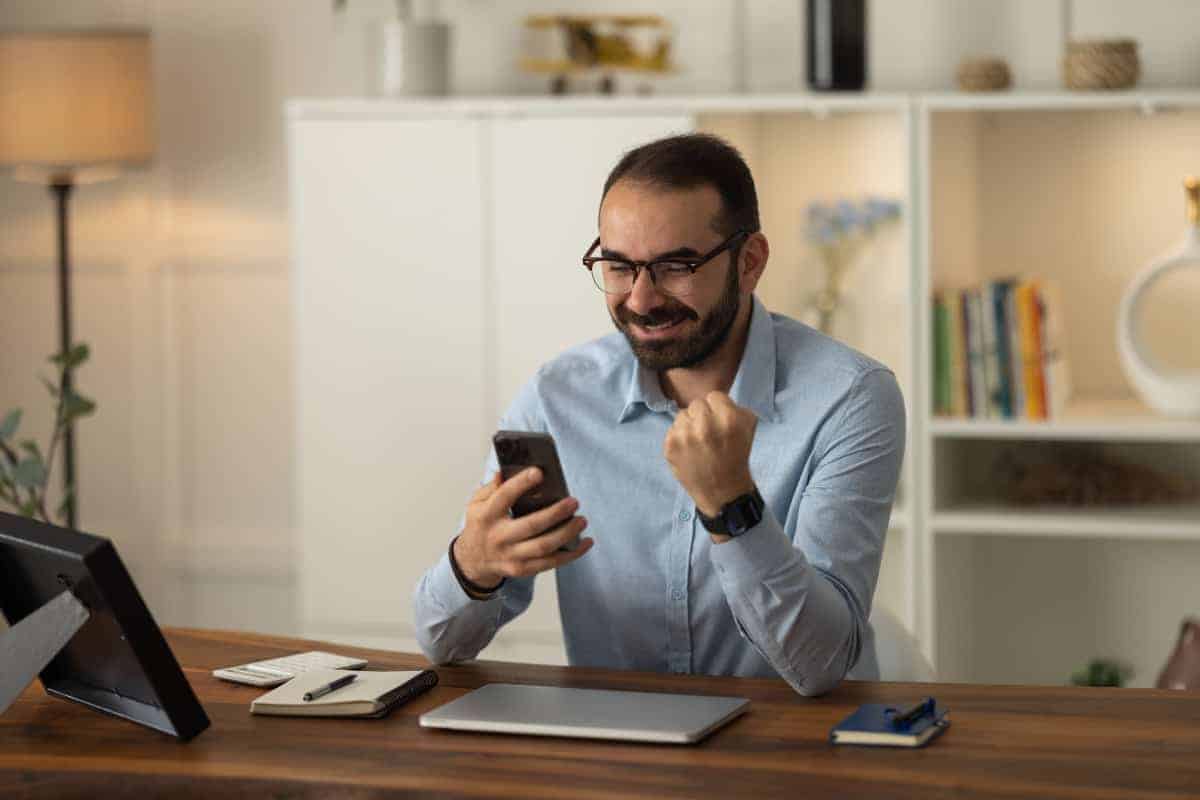 homme content devant téléphone