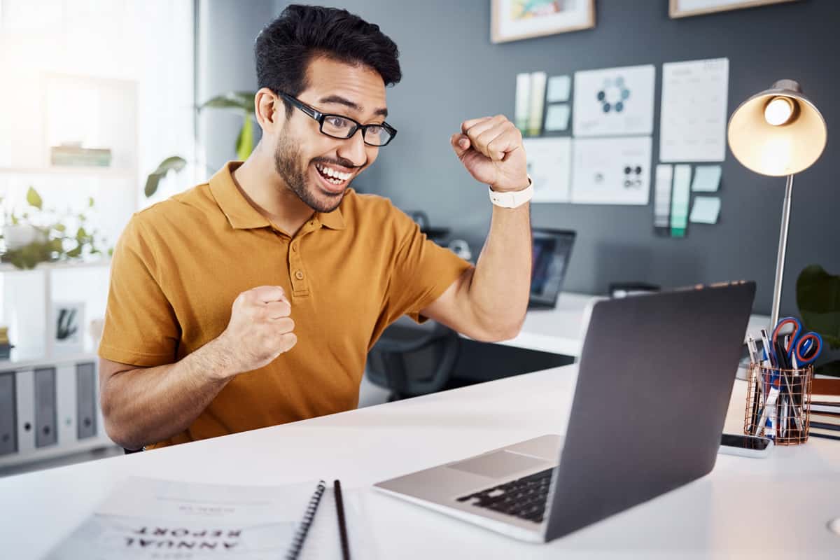 jeune homme content devant ordinateur 