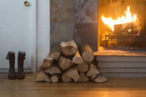 cheminée avec du bois de chauffage sur sa gauche.