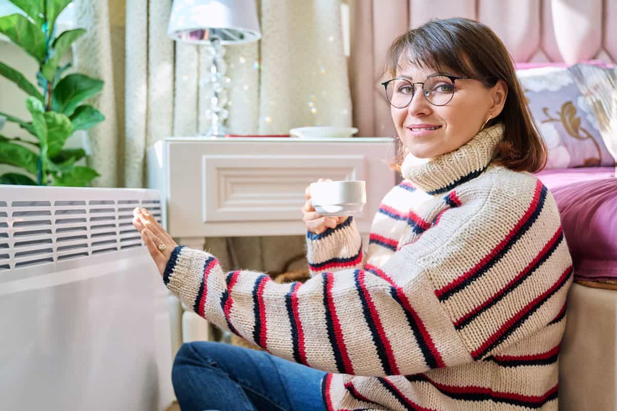 femme se réchauffe devant radiateur